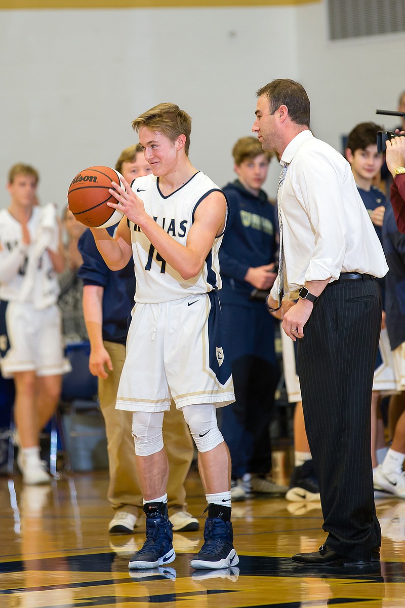 In this 2017 file photo, Landon Harrison of the Helias Crusaders is presented with a commemorative ball by coach Josh Buffington after scoring his 1,000th career point during a game against Hickman at Rackers Fieldhouse.