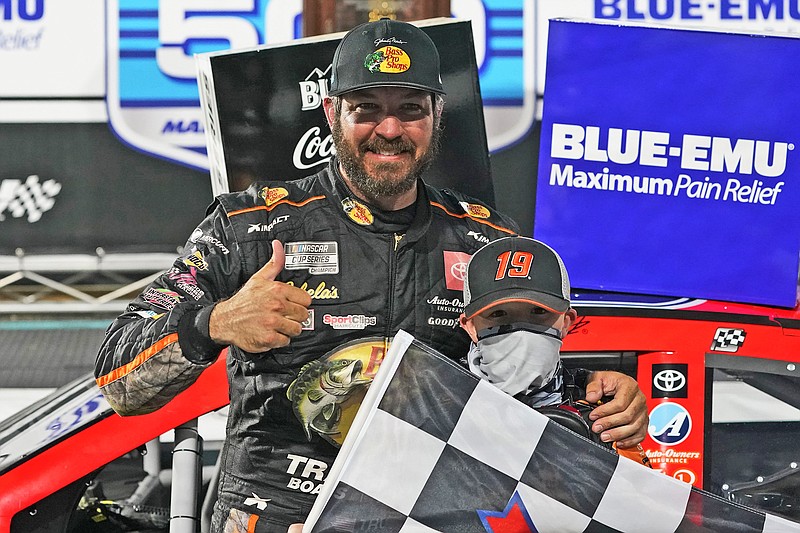 Martin Truex Jr. gives a thumbs-up as he celebrates with a fan after winning last Sunday's NASCAR Cup Series race at Martinsville Speedway in Martinsville, Va.
