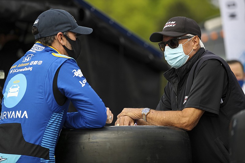 In this image provided by IndyCar, seven-time NASCAR champion Jimmie Johnson speaks Saturday to four-time Indianapolis 500 winner Rick Mears before the first IndyCar practice session of the season at Barber Motorsports Park in Birmingham, Ala.