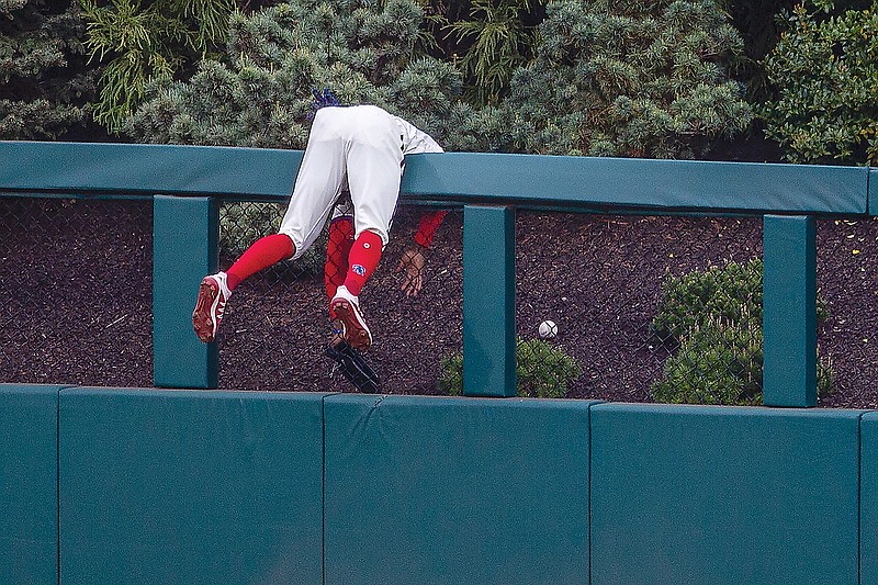Phillies center fielder Roman Quinn hangs over the wall trying to catch a home run hit by Paul DeJong of the Cardinals during the third inning of Saturday's game in Philadelphia.