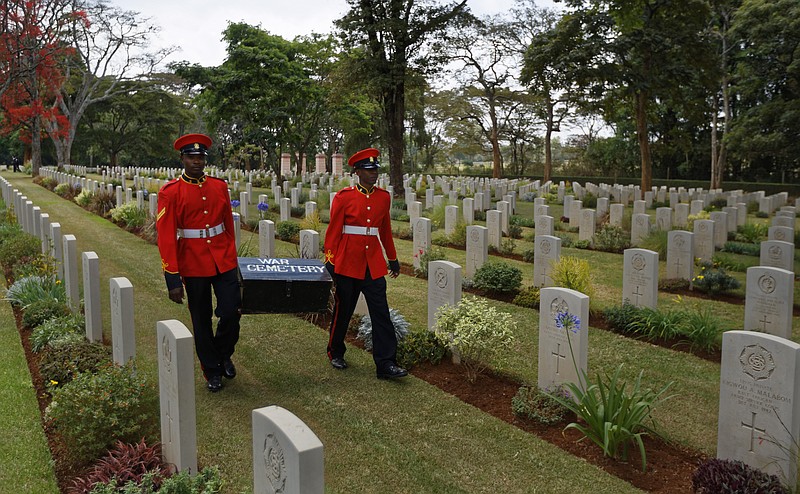 FILE - In this Sunday, Nov. 13, 2016 file photo, two members of Kenya's Military Police walk past graves as they leave after attending a Remembrance Sunday event, to honor the contribution of those British and Commonwealth military who died in the two World Wars and later conflicts, at the Nairobi War Cemetery in Kenya. The Commonwealth War Graves Commission has apologized after an investigation found that at least 161,000 mostly Africans and Indians who died fighting for the British Empire during World War I weren't properly honored due to "pervasive racism", according to findings released Thursday, April 22, 2021. (AP Photo/Ben Curtis, File)