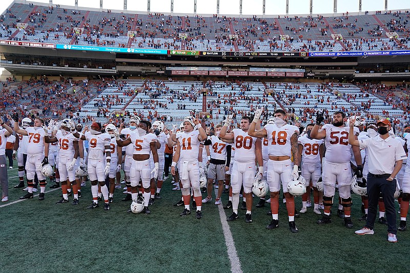 In this Saturday, Oct. 24, 2020, file photo, Texas players, including Sam Ehlinger (11), sing "The Eyes Of Texas" after an NCAA college football game against Baylor in Austin, Texas. The University of Texas marching band and pep band will be required to play "The Eyes of Texas" school song when they return to performing, but the school will also create a new band that doesn't include it in its play list, the school has announced. The song has been mired in controversy since summer 2020 when a group of athletes and students called on the school to ditch the tune amid national racial injustice protests after the killing of George Floyd. (AP Photo/Chuck Burton, File)