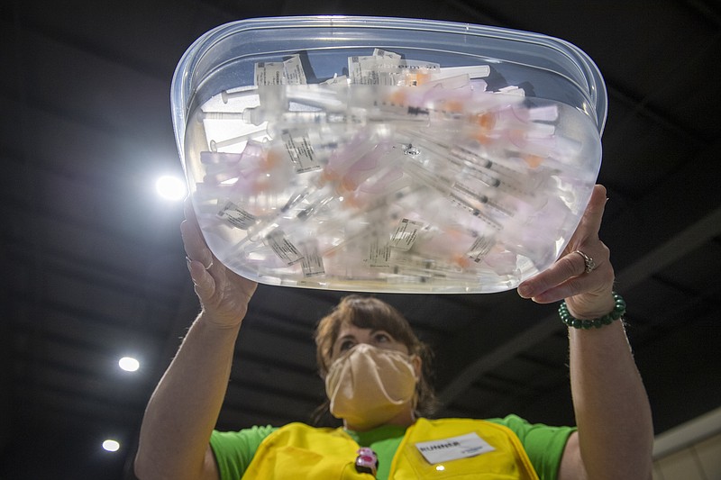 FILE - In this March 10, 2021, file photo, a staff member of Ochsner Health carries a tray filled with syringes containing the Johnson & Johnson COVID-19 vaccine as people come into the Castine Center in Pelican Park to be vaccinated in Mandeville, La. The stark vaccine access gap is prompting increased calls across the world for the U.S. to start shipping vaccine supplies to poorer countries. (Chris Granger/The Times-Picayune/The New Orleans Advocate via AP, File)