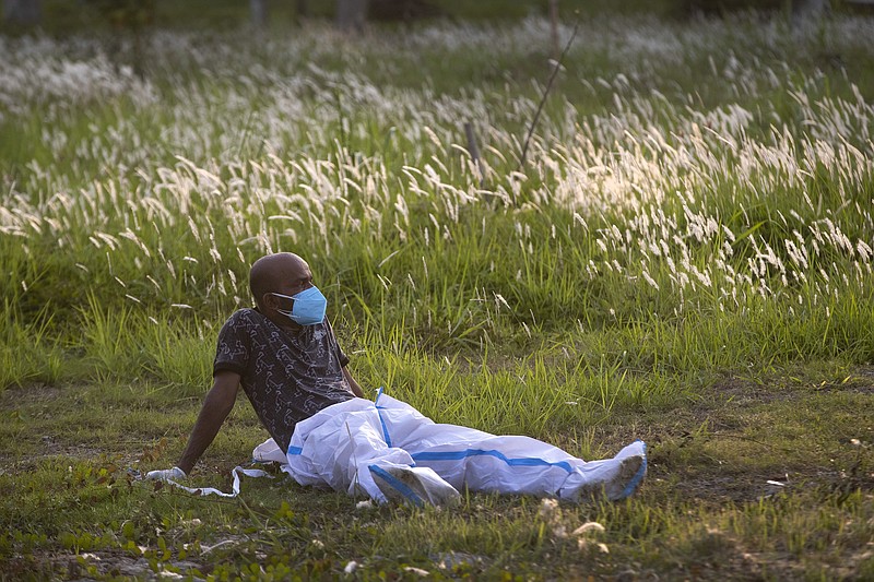 An exhausted municipal worker rests after bringing the body of a person who died of COVID-19 for burial in Gauhati, India, Sunday, April 25, 2021. As India suffers a bigger, more infectious second wave with a caseload of more than 300,000 new cases a day, the country’s healthcare workers are bearing the brunt of the disaster. (AP Photo/Anupam Nath)