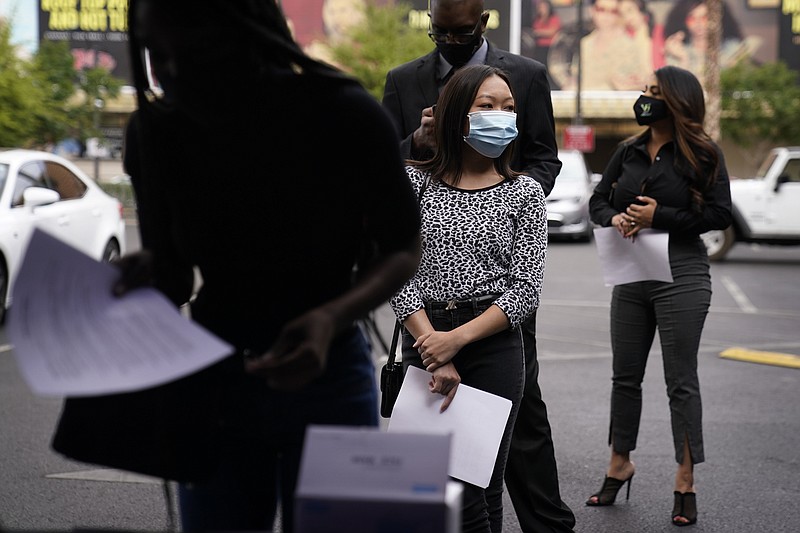 People wait in line, resumes in hand, while waiting to apply for jobs during an outdoor hiring event for the Circa resort and casino, Tuesday, April 27, 2021, in Las Vegas.  The number of Americans applying for unemployment benefits dropped by 13,000 last week to 553,000, the lowest level since the pandemic hit last March and another sign the economy is recovering from the coronavirus recession.  (AP Photo/John Locher)