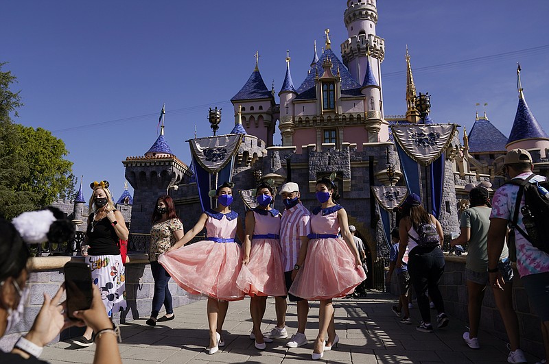 A family takes a photo in front of Sleeping Beauty's Castle at Disneyland in Anaheim, Calif., Friday, April 30, 2021.  The iconic theme park in Southern California that was closed under the state's strict virus rules swung open its gates Friday and some visitors came in cheering and screaming with happiness. (AP Photo/Jae Hong)