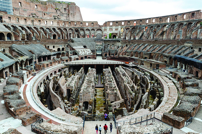In this April 26, 2021 file photo,  few visitors arrive for their tour of the ancient Colosseum, in Rome. Italy's culture ministe Dario Franceschini announced Sunday, May 2, 2021  project to build and install a retractable structure, a high-tech, light-weight stage inside the Roman Colosseum which will allow visitors a central viewpoint from within the ancient structure "to see the majesty of the monument." The stage had existed until the 1800s when it was removed for archaeological digs on the subterranean levels of the ancient structure. (AP Photo/Domenico Stinellis, file)