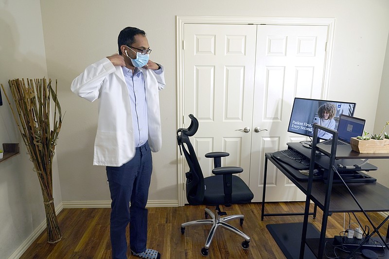 Medical director of Doctor on Demand Dr. Vibin Roy prepares to conduct an online visit with a patient from his work station at home, Friday, April 23, 2021, in Keller, Texas. Some U.S. employers and insurers want you to make telemedicine your first choice for most doctor visits. Retail giant Amazon and several insurers have started or expanded virtual-first care plans to get people thinking telemedicine routinely, even for annual checkups.  (AP Photo/LM Otero)