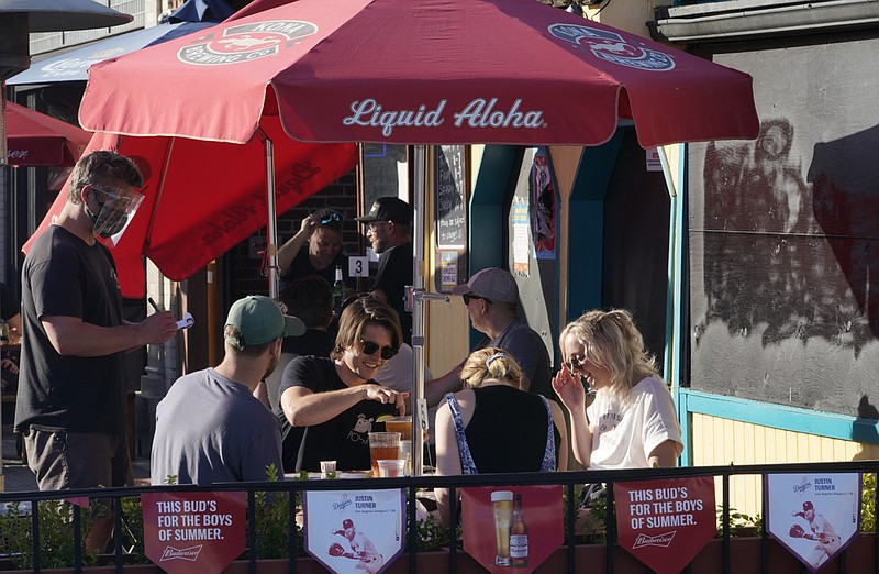 FILE - In this March 31, 2021 file photo, people drink outdoors on the patio of Big Dean's Ocean Front Cafe, decorated with beer banners with the image of Los Angeles Dodgers's Justin Turner, in Santa Monica, Calif. Thousands of restaurants and bars decimated by COVID-19 have a better chance at survival as the government begins handing out $28.6 billion in grants _ money to help these businesses stay afloat while they wait for customers to return. The Small Business Administration is accepting applications for grants from the Restaurant Revitalization Fund as of Monday, May 3.  (AP Photo/Damian Dovarganes, File)