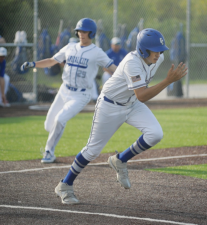 Carlos Ayala of Capital City sprints toward first base after laying down a bunt to score teammate Brett Kuebler (background) during Monday's game against Lebanon at Capital City High School.