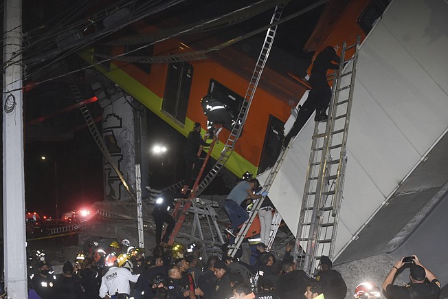 Mexico City fire fighters and rescue personnel work to recover victims from a subway car that fell after a section of Line 12 of the subway collapsed in Mexico City, Monday, May 3, 2021. The section passing over a road in southern Mexico City collapsed Monday night, dropping a subway train, trapping cars and causing at least 50 injuries, authorities said. (AP Photo/Jose Ruiz)