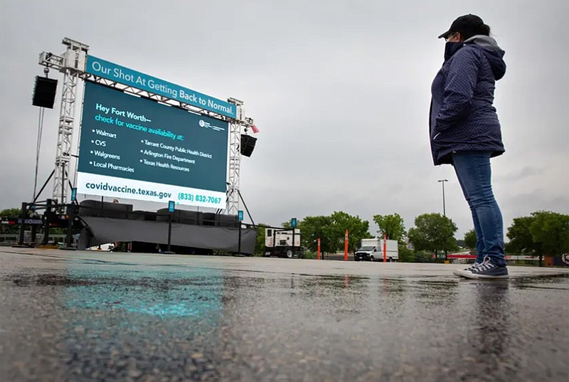 Susan Valadez looks at a Texas Department of State Health Services advertisement encouraging people to get the COVID-19 vaccine on Friday before she enters a Walmart in Fort Worth. (Photo by Shelby Tauber for The Texas Tribune)
