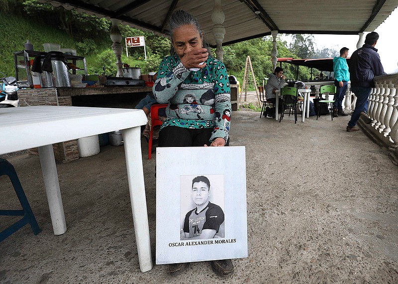 Doris Tejada, mother of Oscar Alexander Morales who disappeared on New Year's eve 2007, holds a photo of her son, at a shop in Soacha, Colombia, Thursday, April 8, 2021. Tejada and her husband found out that their son indeed is on the list of the "false positives," victims of extrajudicial executions by members of Colombia's army who were falsely presented as guerrillas killed in combat during the country's internal conflict, which ended with the 2016 demobilization of the Revolutionary Armed Forces of Colombia. (AP Photo/Fernando Vergara)