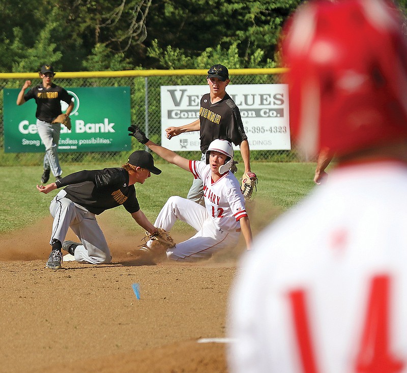 Calvary Lutheran's Jesse Jorgensen slides underneath the tag of Vienna's Lucas Magner for a stolen base as Calvary's Jared Braun looks on from the batter's box Thursday at Calvary Lutheran High School.