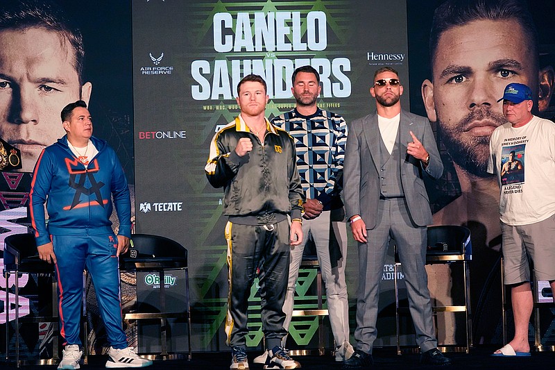 Boxers Canelo Alvarez of Mexico, center left, and Billy Joe Saunders of Great Britain, center right, pose for cameras as promoter Eddie Hearn, center, trainer Eddy Reynoso, left, and Saunders' father Tommy Saunders, right, all look on during a pre-fight news conference, Thursday, May 6, 2021, in Arlington, Texas. Alvarez and Saunders fight on Saturday, May 8, 2021, for the unified super middleweight world championship. (AP Photo/LM Otero)