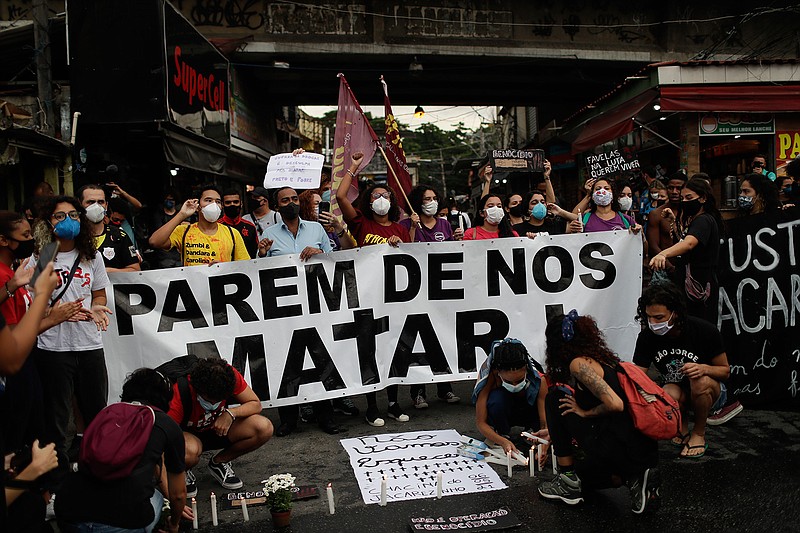 Activists and victim's relatives light candles and hold the Portuguese message: "Stop killing us" the day after a deadly police operation in the Jacarezinho favela of Rio de Janeiro, Brazil, Friday, May 7, 2021. A bloody, hours-long gunbattle here echoed into Friday, with authorities saying the police mission killed two dozen criminals while residents and activists claimed human rights abuses. (AP Photo/Silvia Izquierdo)