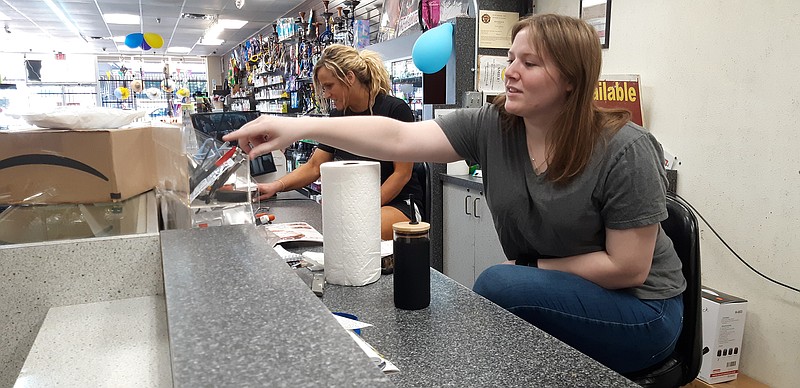 Kourtney Teel directs a customer to sought-after merchandise at Moon Smoke and Gift. The store offers a wide range of items designed to be gifts to create memories, though many customers become regulars after their first visit.