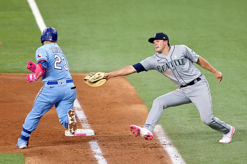 Texas Rangers catcher Jose Trevino (23) evades a tag by Seattle Mariners first baseman Evan White (12) as he makes it safely to first during the fifth inning of a baseball game Sunday, May 9, 2021, in Arlington, Texas. (AP Photo/Michael Ainsworth)