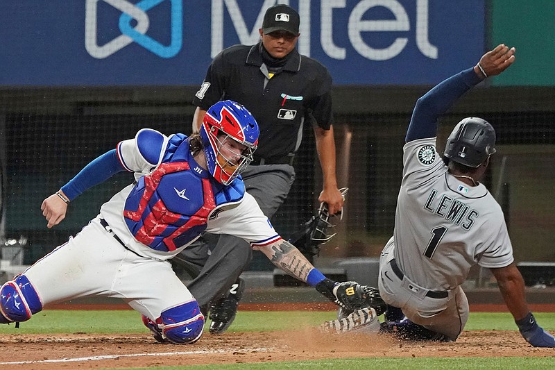Seattle Mariners base runner Kyle Lewis is tagged out at home by Texas Rangers catcher Jonah Heim to end a baseball game in the ninth inning Saturday, May 8, 2021, in Arlington, Texas. (AP Photo/Louis DeLuca)
