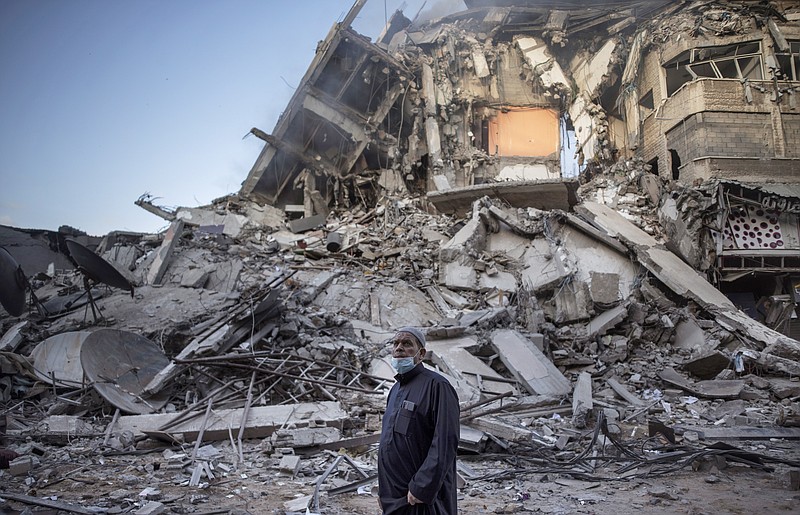 A Palestinian man looks at the destruction of a building hit by Israeli airstrikes in Gaza City, Thursday, May 13, 2021. Gaza braced for more Israeli airstrikes and communal violence raged across Israel after weeks of protests and violence in Jerusalem. (AP Photo/Khalil Hamra)