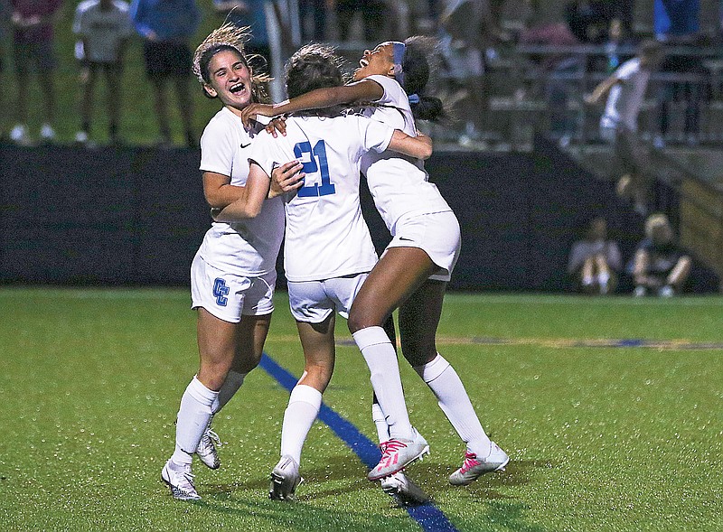 Capital City's Georgia Pardalos (left) and Ayanna Clarke (right) rush teammate Kourtney Blatz (center) after she made the last penalty kick during the shootout portion of Tuesday's Class 4 District 9 semifinal game against Helias at the Crusader Athletic Complex.