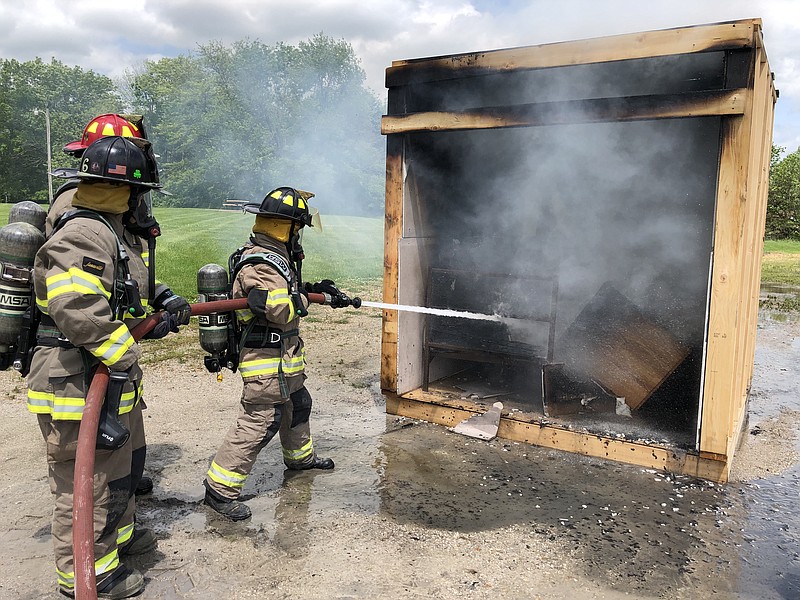 Ryan Boland/FULTON SUNFulton High School senior Kayanna Gaines (front) and science teacher Liz Schwab put out the blaze during a dorm room fire simulation presented by the Fulton Fire Department on Wednesday at the high school.