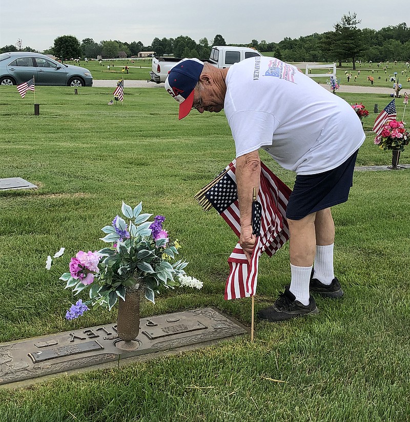 David Beaver, commander of American Legion Kingdom Post 210, places an American flag on a military veteran's grave Tuesday morning, May 25, 2021, at Callaway Memorial Gardens in Fulton.