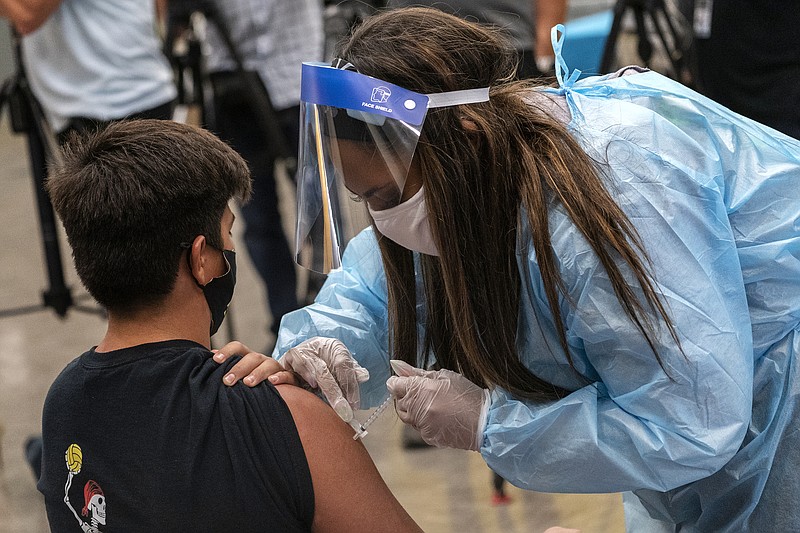 High school water polo team member Marc Bugarin, 15, is vaccinated at a school-based COVID-19 vaccination clinic for students 12 and older in San Pedro, Calif., Monday, May 24, 2021. School districts from California to Michigan are offering free prom tickets and deploying mobile vaccination teams to schools to inoculate students 12 and up so everyone can return to classrooms in the fall. They are also enlisting students who have gotten shots to press their friends to do the same. (AP Photo/Damian Dovarganes)