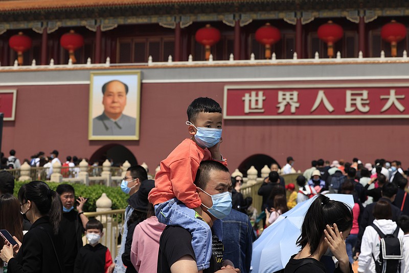 FIEL - In this May 3, 2021, file photo, a man and child wearing masks visit Tiananmen Gate near the portrait of Mao Zedong in Beijing. China’s ruling Communist Party is looking at allowing easing birth limits further to allow couples to have three children instead of two in response to the population's rising age, a state news agency said Monday, May 31, 2021. (AP Photo/Ng Han Guan, File)