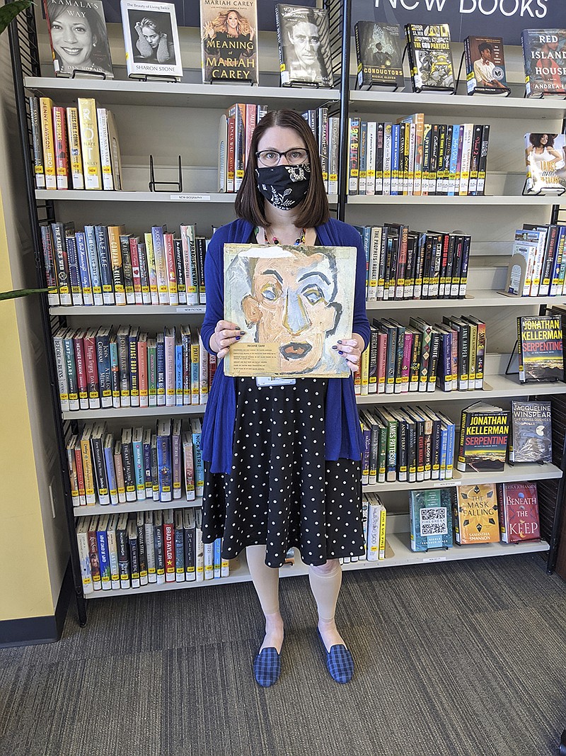 In this photo provided by Heights Libraries, Sara Phillips, a branch manager with Heights Libraries in Ohio, holds the Bob Dylan double album "Self Portrait" borrowed in 1973 by eighth-grader Howard Simon he returned recently 48 years overdue. (Heights Libraries via AP)