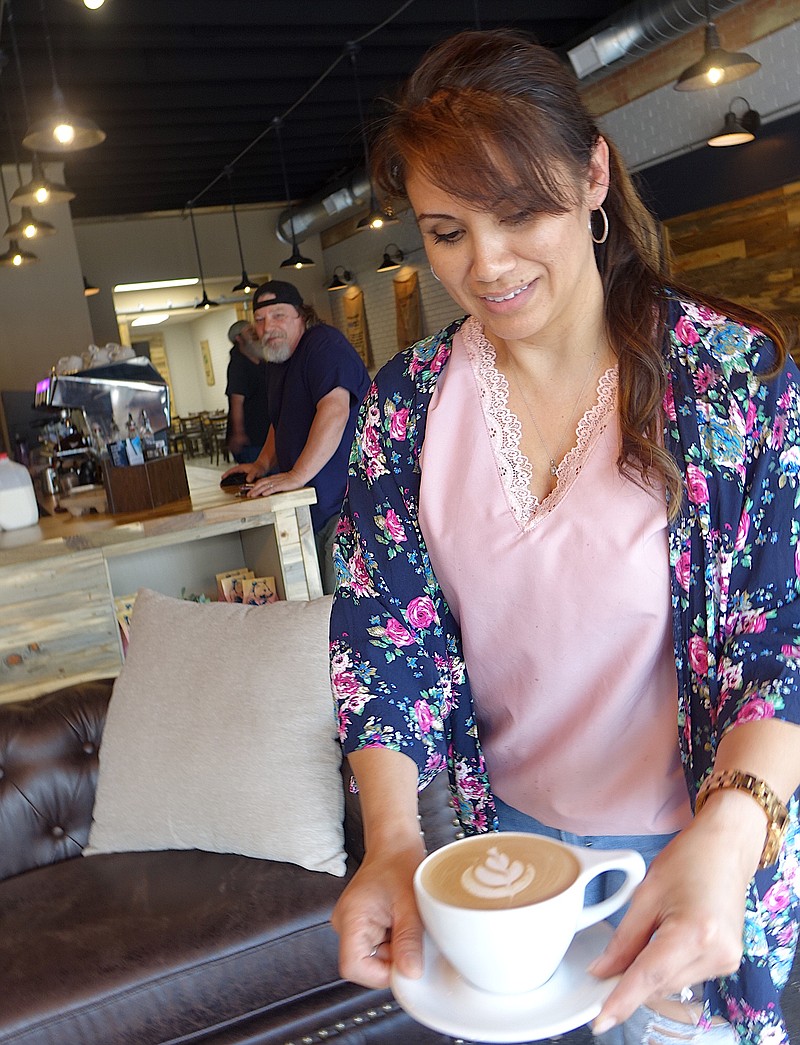 Tanya Beers shows both the special coffee cup and saucer with which her special coffee is delivered. Beers makes the creative design on the surface of the coffee itself.
