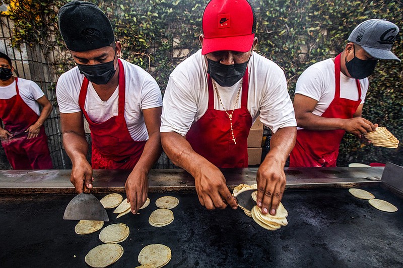 Workers work at a quick pace as customers line up for tacos at the Avenue 26 night market in Lincoln Heights on Friday, May 14, 2021 in Los Angeles, California. (Francine Orr/Los Angeles Times/TNS)