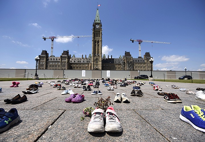 Dried flowers rest inside a pair of child's running shoes at a memorial for the 215 children whose remains were found at the grounds of the former Kamloops Indian Residential School at Tk'emlups te Secwépemc First Nation in Kamloops, B.C., on Parliament Hill in Ottawa on Friday, June 4, 2021.  (Justin Tang/The Canadian Press via AP)