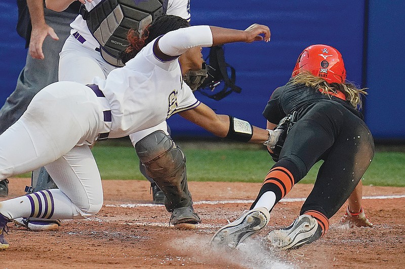 Oklahoma State's Scotland David is tagged out at home plate by James Madison pitcher Odicci Alexander in the seventh inning of Friday night's Women's College World Series game in Oklahoma City.