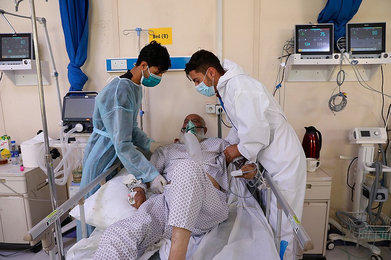 Sons help with their father at the Afghan-Japan Communicable Disease Hospital in Kabul, Afghanistan, Sunday, May 30, 2021. Afghanistan is battling a brutal third wave of COVID infections, while health officials plead for vaccines, expressing deep frustration at the inequities of the global vaccine distribution. Positive COVID cases jump from eight percent to 60 per cent in some parts of the country. (AP Photo/Rahmat Gul)