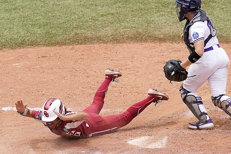 Oklahoma's Rylie Boone (left) celebrates after scoring behind James Madison catcher Lauren Bernett on a hit by an Tiara Jennings in the seventh inning of Sunday's NCAA Women's College World Series game in Oklahoma City.