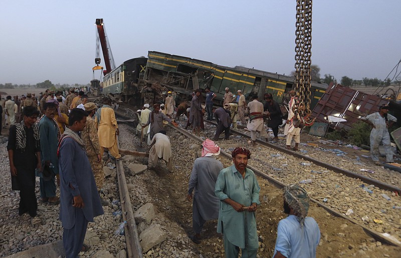 Railway workers rebuild the track at the track at the site of a train collision in the Ghotki district, southern Pakistan, Monday, June 7, 2021. An express train barreled into another that had derailed in Pakistan before dawn Monday, killing dozens of passengers, authorities said. More than 100 were injured, and rescuers and villagers worked throughout the day to search crumpled cars for survivors and the dead. (AP Photo/Fareed Khan)