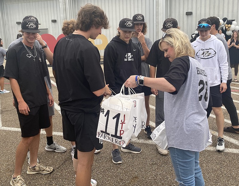 Jenny Bearden and her son Brock hand out goodie bags to the Pleasant Grove High School baseball team Tuesday at the school. The team will face Stephenville on Wednesday in Austin in the semifinal round of the 4A state championship tournament.