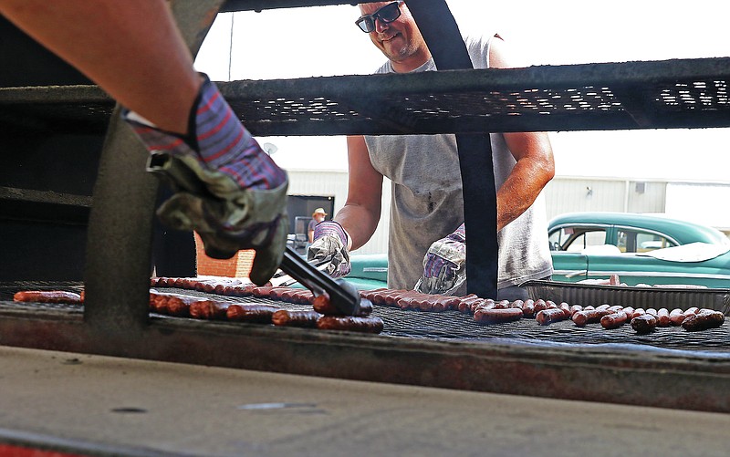 Joshua Stockman, a sergeant for the Cole County Sheriff's Department, flips hot dogs on a grill Tuesday evening, June 8, 2021, during the department's annual barbecue at the Jefferson City Jaycees Fairgrounds. (Jason Strickland/News Tribune photo)