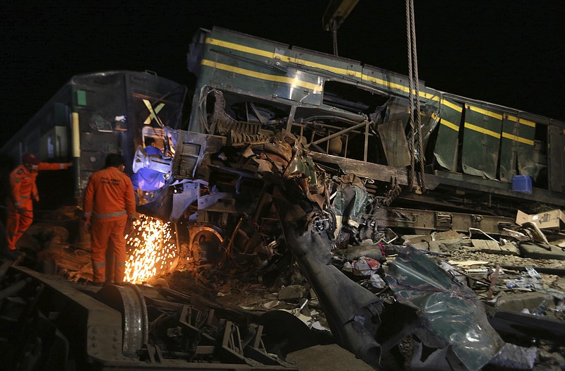 Railway workers try to clear the track at the site of a train collision in the Ghotki district, southern Pakistan, late Monday, June 7, 2021. An express train barreled into another that had derailed in Pakistan before dawn Monday, killing dozens of passengers, authorities said. More than 100 were injured, and rescuers and villagers worked throughout the day to search crumpled cars for survivors and the dead. (AP Photo/Fareed Khan)