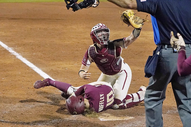Oklahoma's Lynnsie Elam (right) gestures to the home plate umpire, who calls Florida State's Josie Muffley safe at home plate due to obstruction in the seventh inning in the first game of the Women's College World Series championship series Tuesday in Oklahoma City.
