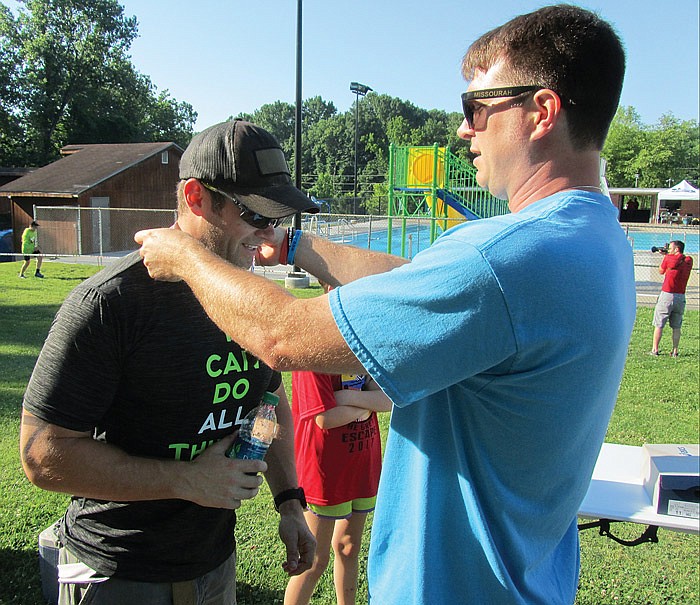 In this June 11, 2017 News Tribune file photo: At right, Kris Wilson of the Jefferson City Convention and Visitors Bureau places a medal around the neck of Corey Case after Case comes through the finish line at the second annual Jefferson City Triathlon: The Great Escape. Case, of Ashland, was part of the winning relay team which also included Abbie Schattgen and Charlie Schattgen.