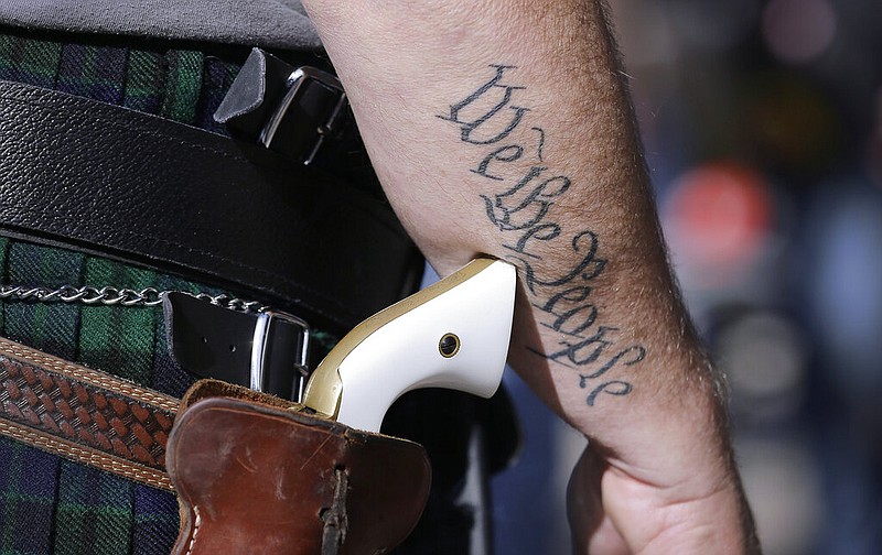 In this Jan. 26, 2015, file photo, a supporter of open carry gun laws wears a pistol as he prepares for a rally in support of open carry gun laws at the Capitol in Austin, Texas. Texas lawmakers have given final approval to allowing people to carry handguns without a license, or the background check and training that go with it. The Republican-dominated Legislature approved the measure Monday, May 24, 2021, sending it to Gov. Greg Abbott.