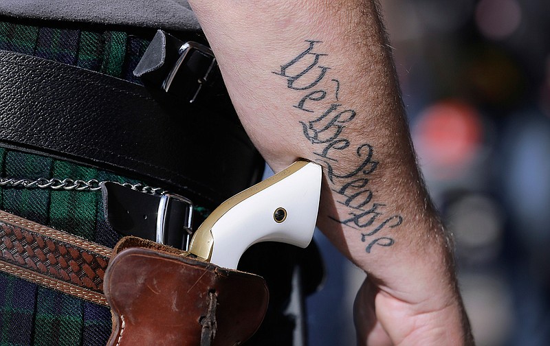 In this Jan. 26, 2015 file photo, a supporter of open carry gun laws, wears a pistol as he prepares for a rally in support of open carry gun laws at the Capitol, in Austin, Texas. Texas lawmakers have given final approval to allowing people carry handguns without a license, and the background check and training that go with it. The Republican-dominated Legislature approved the measure Monday, May 24, 2021 sending it to Gov. Abbott. (AP Photo/Eric Gay, File)