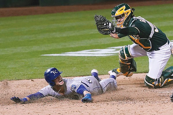 Andrew Benintendi of the Royals looks for the call after being tagged out at home by Athletics catcher Aramis Garcia during the eighth inning of Friday night's game in Oakland, Calif.
