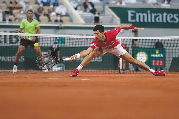 Novak Djokovic stretches to return the ball to Rafael Nadal during Friday's semifinal match at the French Open in Paris.