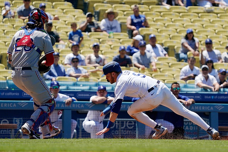 Los Angeles Dodgers' Gavin Lux, right, falls before being tagged out by Texas Rangers catcher Jonah Heim after getting caught between third and home during the third inning of a baseball game Sunday, June 13, 2021, in Los Angeles. (AP Photo/Mark J. Terrill)