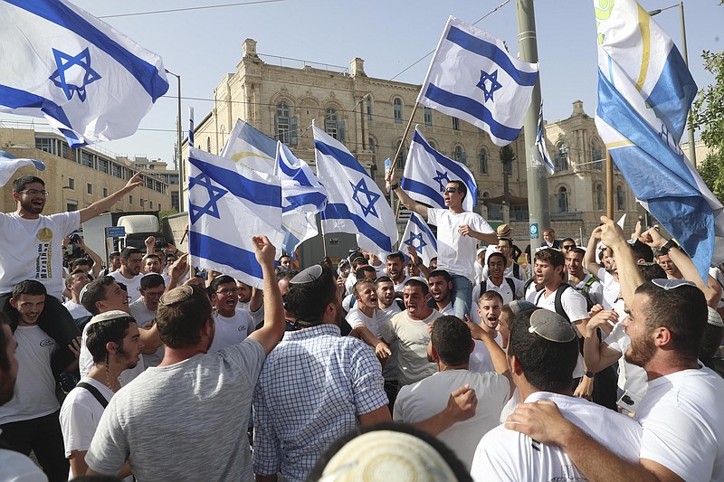 FILE - In this May 10, 2021, file photo, Israelis wave national flags during a Jerusalem Day parade, in Jerusalem. Israel’s new government on Monday, June 14 approved a contentious parade by Israeli nationalists through Palestinian areas around Jerusalem's Old City, setting the stage for possible renewed confrontations just weeks after an 11-day war with Hamas militants in the Gaza Strip. Hamas called on Palestinians to “resist” the march.  (AP Photo/Ariel Schalit, File)