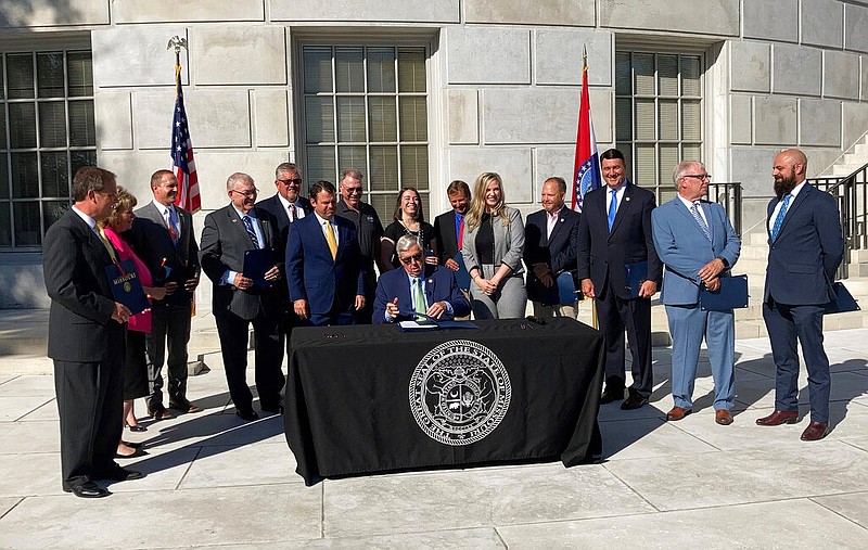 Missouri Gov. Mike Parson signs a copy of a bill limiting the duration of local public health orders during a ceremony Tuesday, June 15, 2021 outside the state Capitol in Jefferson City, Mo. Parson signed a couple dozen copies of the legislation and provided them to lawmakers and others who had supported the measure, including representatives of the restaurant industry. (AP Photo/David A. Lieb)