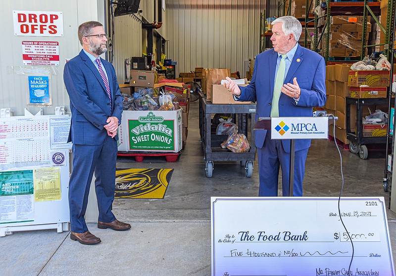 <p>Julie Smith/News Tribune</p><p>Joe Pierle, left, CEO of Missouri Primary Care Association, and Gov. Mike Parson carry on an exchange during a news conference Tuesday at The Samaritan Center. Pierle was on site to deliver a donation to The Samaritan Center and the Food Bank for Central and Northeast Missouri.</p>